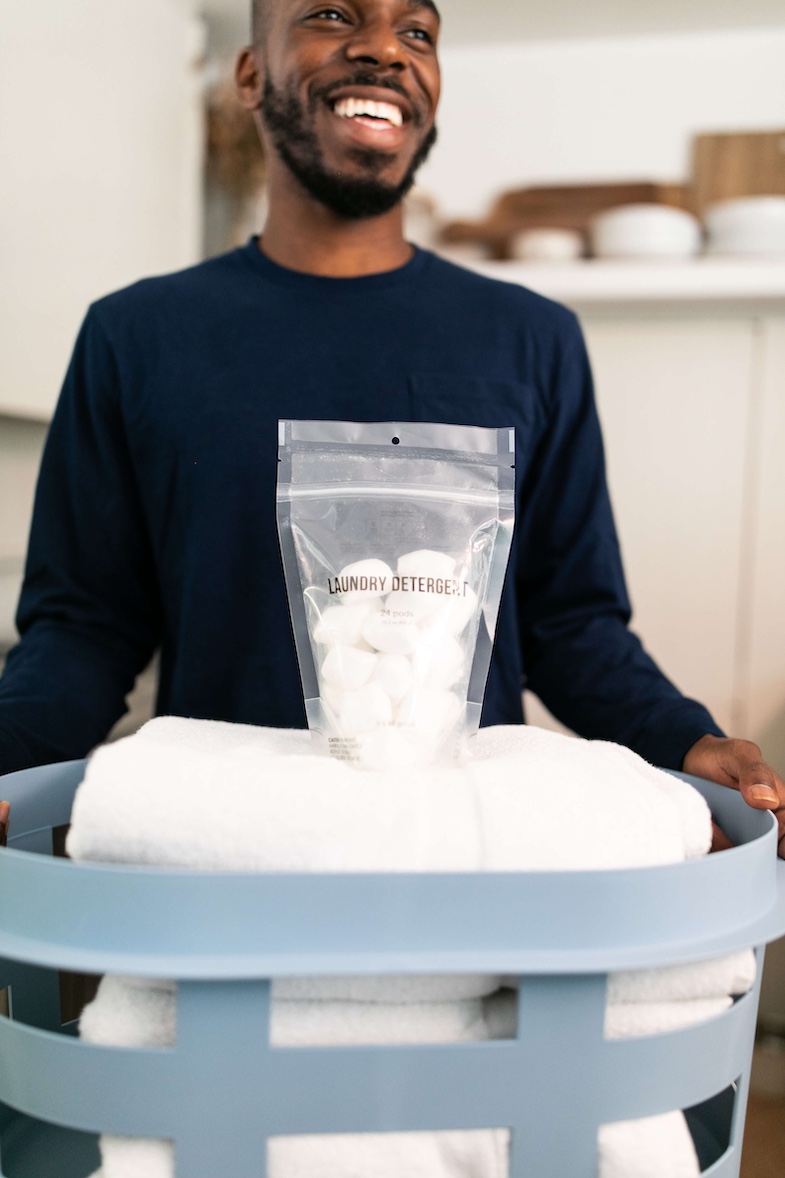 Man carrying laundry with detergent that he is trying for Field Agent's product research.