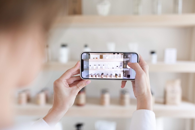 Woman taking a picture of products displayed on a shelf.